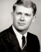 A black-and-white photo of Charles Koch as a young man with neatly combed hair wearing a dark suit, white shirt and a dark tie.