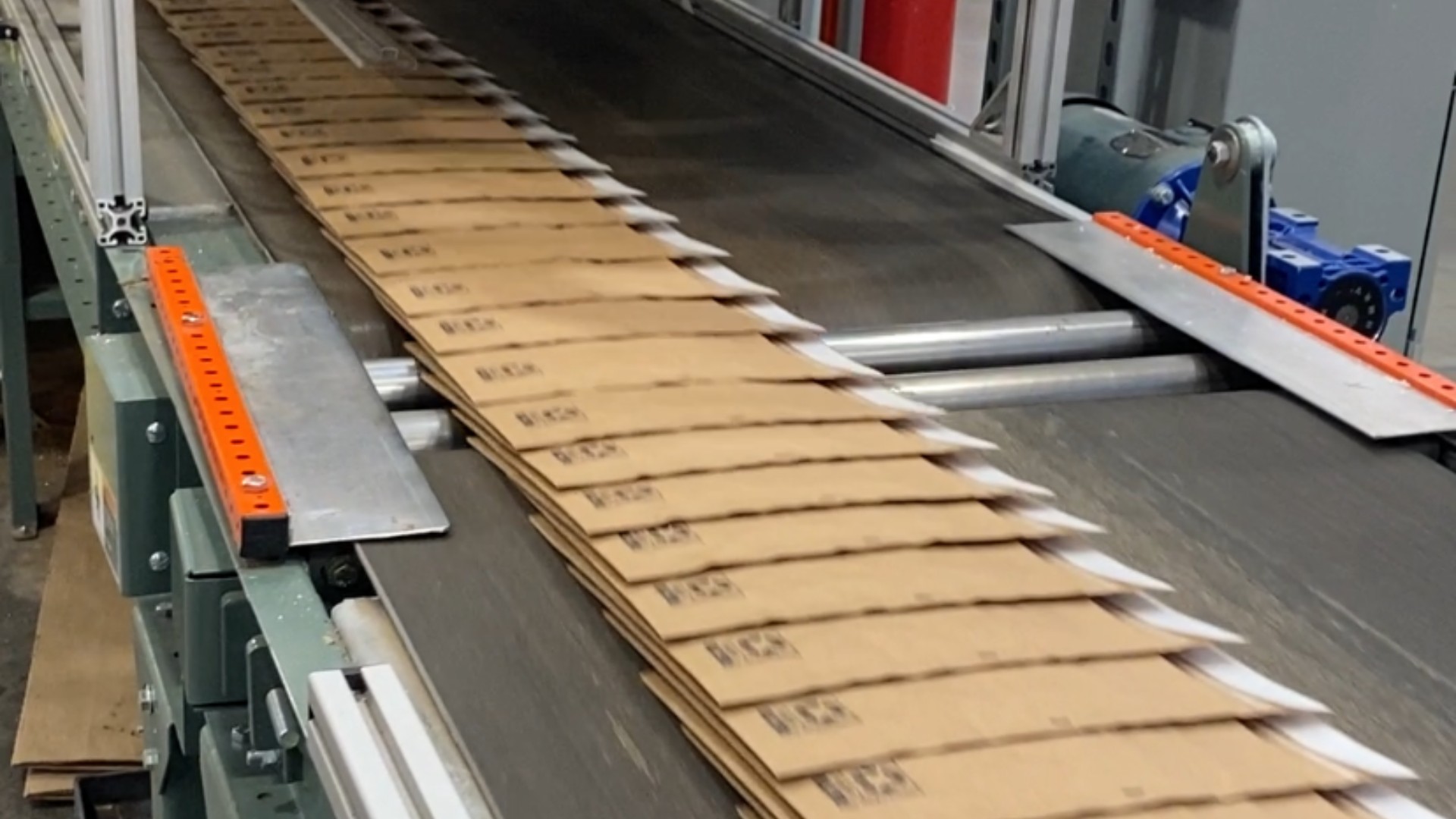 Padded and unpadded mailers travel on a conveyor belt in a manufacturing facility. 