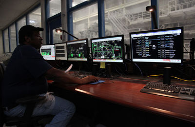 a man sitting at a desk with several computer screens