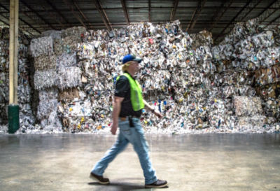 a man walking in a large room with a large pile of garbage
