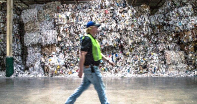 a man walking in a large room with a large pile of garbage