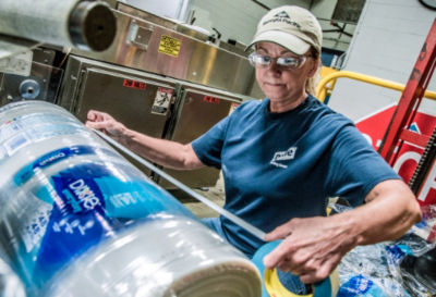 a woman in a factory packing plastic bottles
