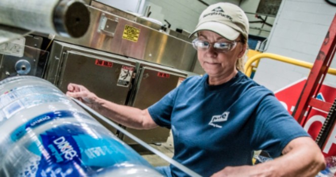 a woman in a factory packing plastic bottles