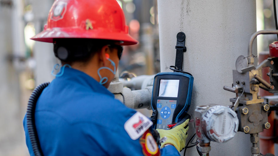 a person in a hard hat using a meter