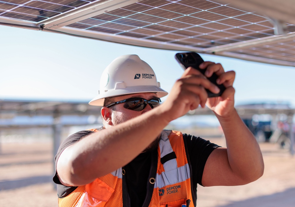a man in a hard hat and sunglasses holding a cellphone
