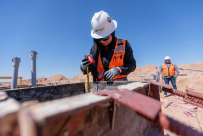 a woman in a hard hat measuring a beam