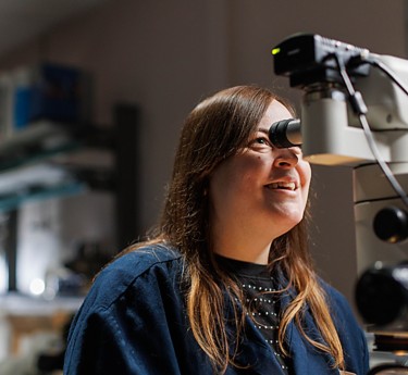 a woman looking through a microscope