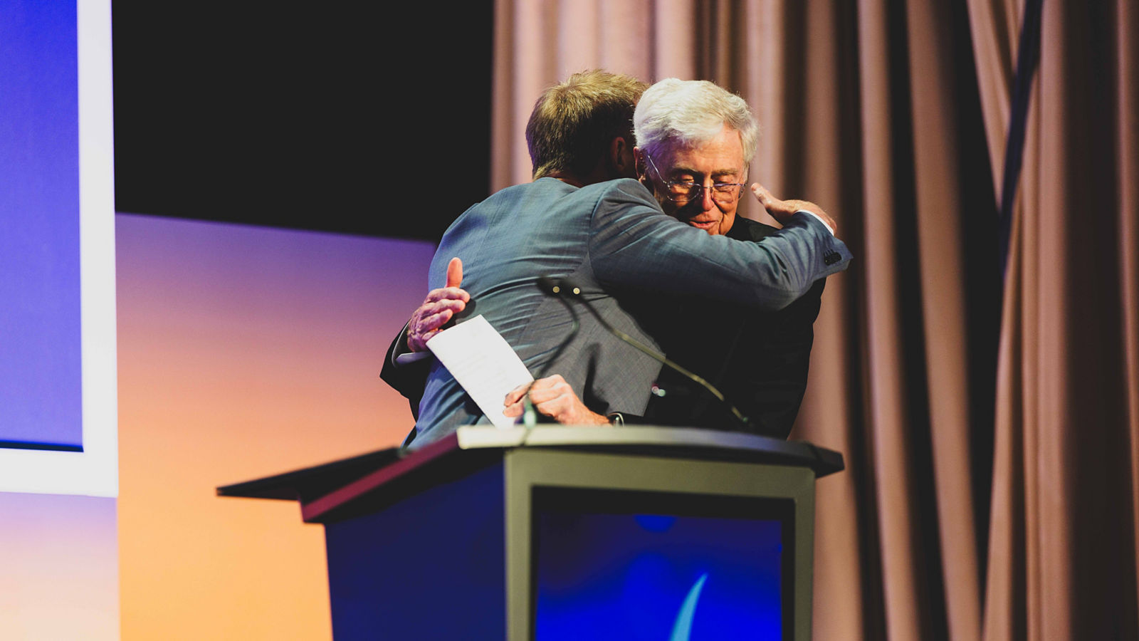 two men hugging at a podium