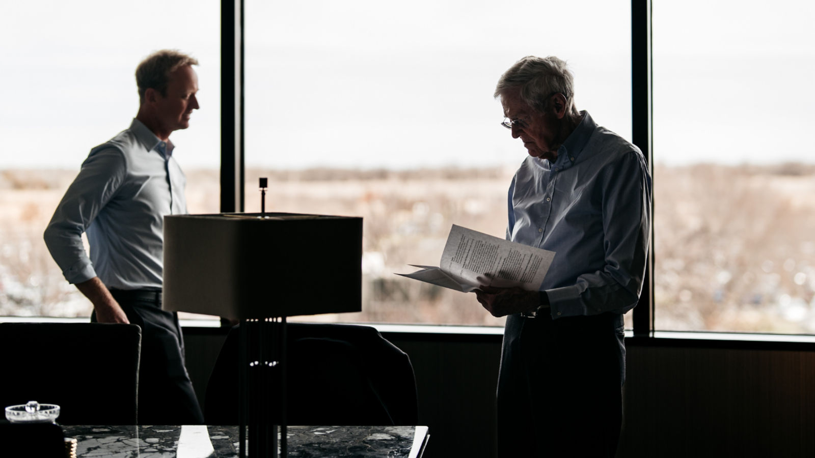 a man standing next to a man holding a paper