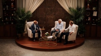 men sitting in chairs on a round stage