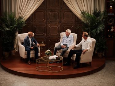 men sitting in chairs on a round stage