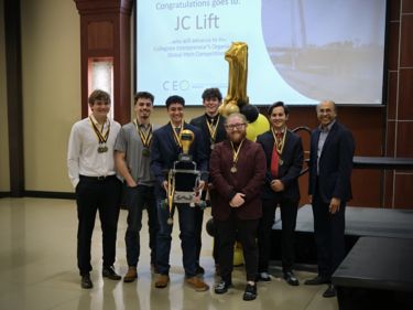 a group of men standing in front of a large screen