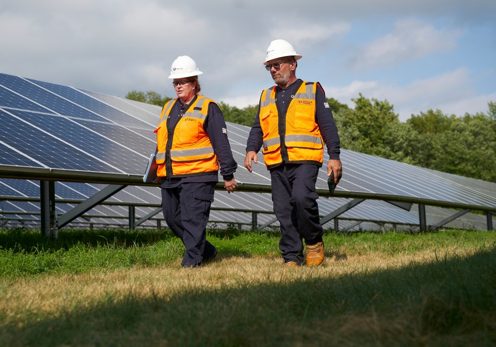 a couple of workers walking in front of solar panels