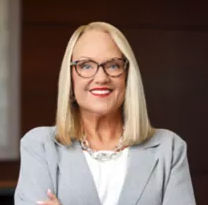 a woman wearing glasses and a grey suit