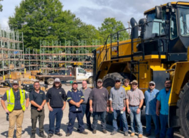 a group of people standing in front of a large yellow vehicle