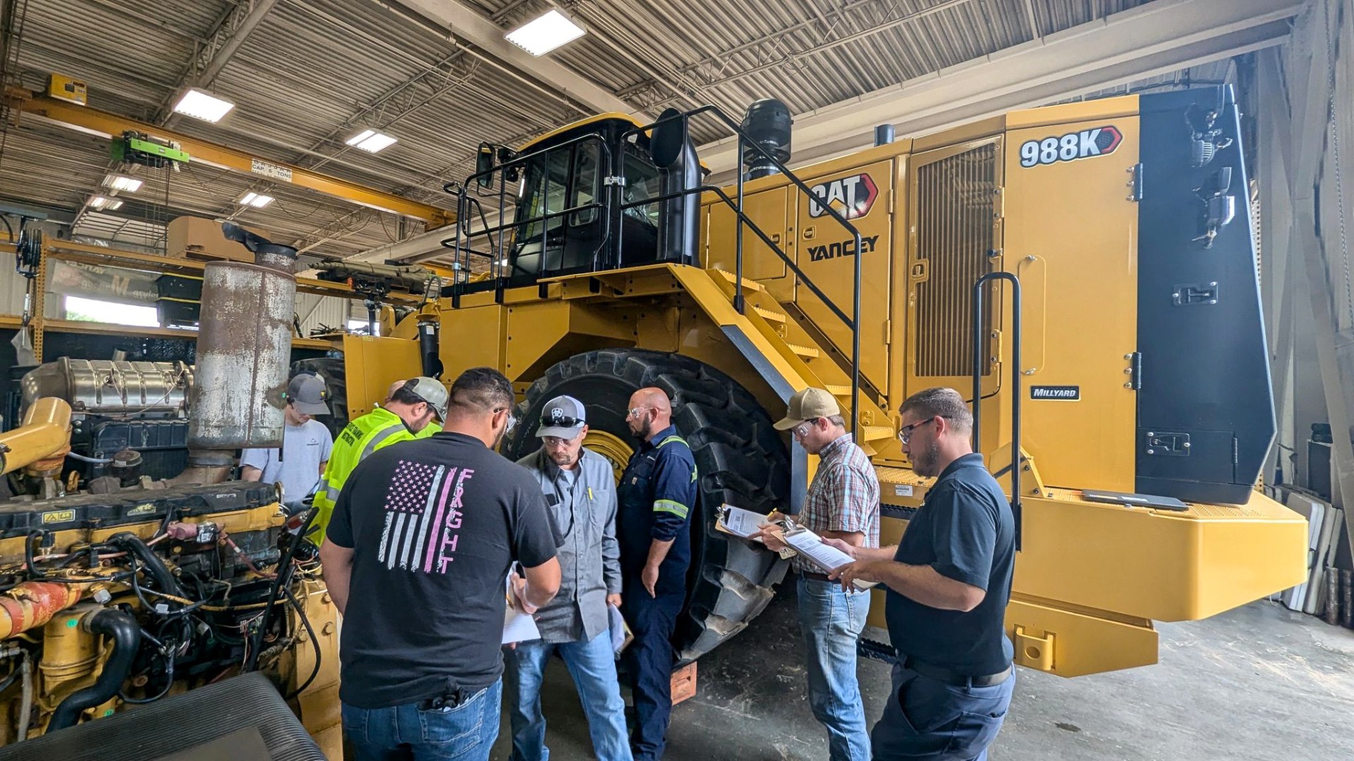Georgia-Pacific employees are outside standing in front of equipment and receiving training on Caterpillar