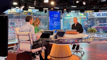 a few people sitting at a table in a news room