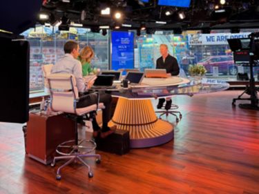 a few people sitting at a table in a news room