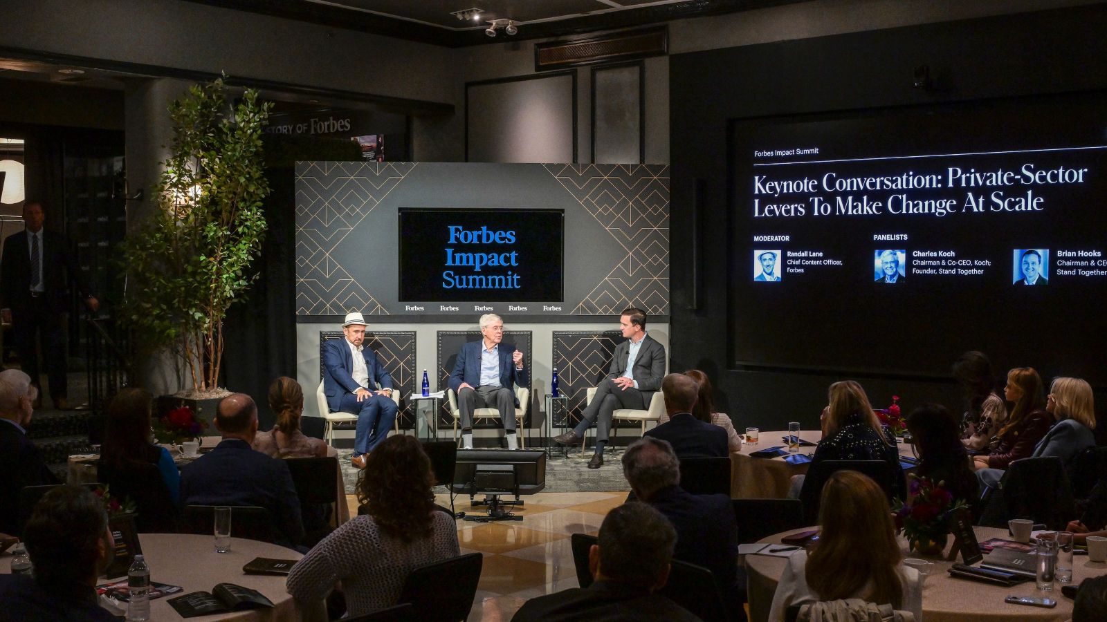 a group of people sitting in chairs in a room with a screen