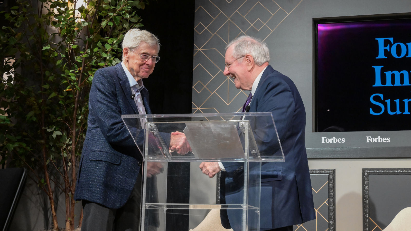 two men shaking hands at a podium