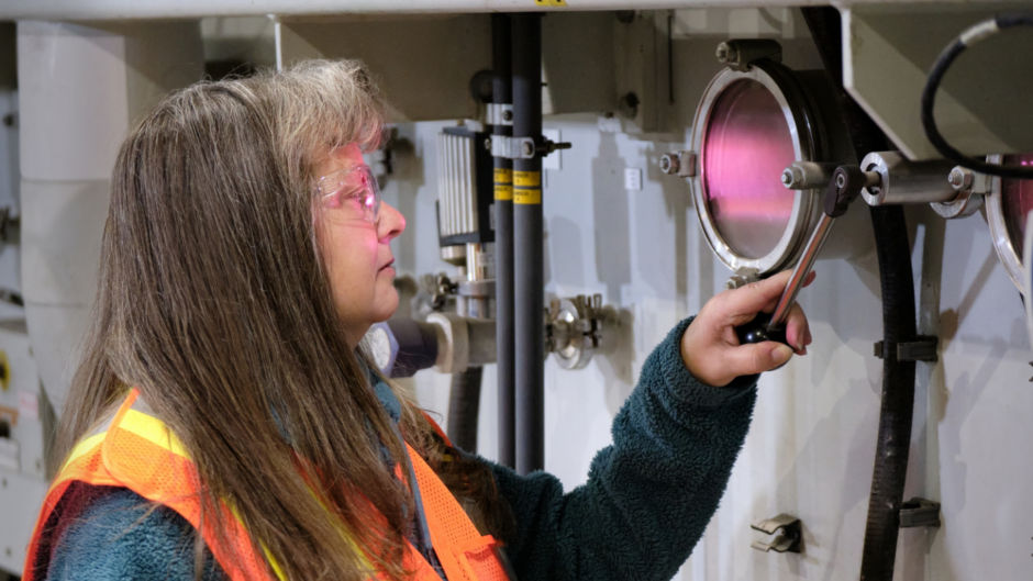 a woman in a safety vest working on a machine