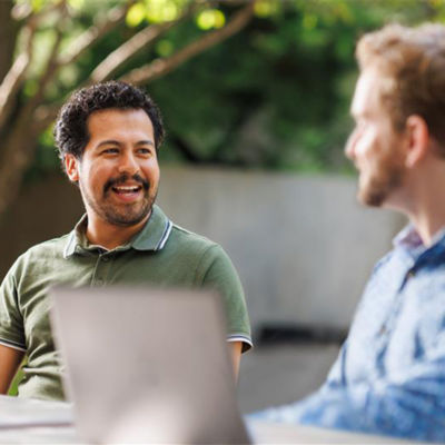 Charles Koch and Chase Koch seated on a stage, talking to a crowd of summer interns in the foreground.