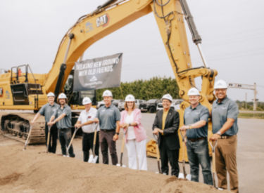 a group of people holding shovels in front of a construction vehicle