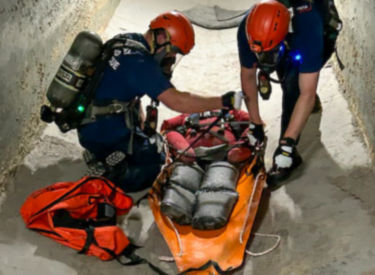 a group of people wearing helmets and carrying a person on a stretcher