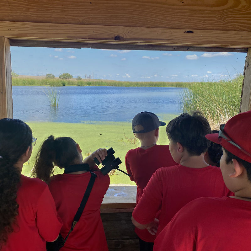 a group of people in red shirts looking out a window