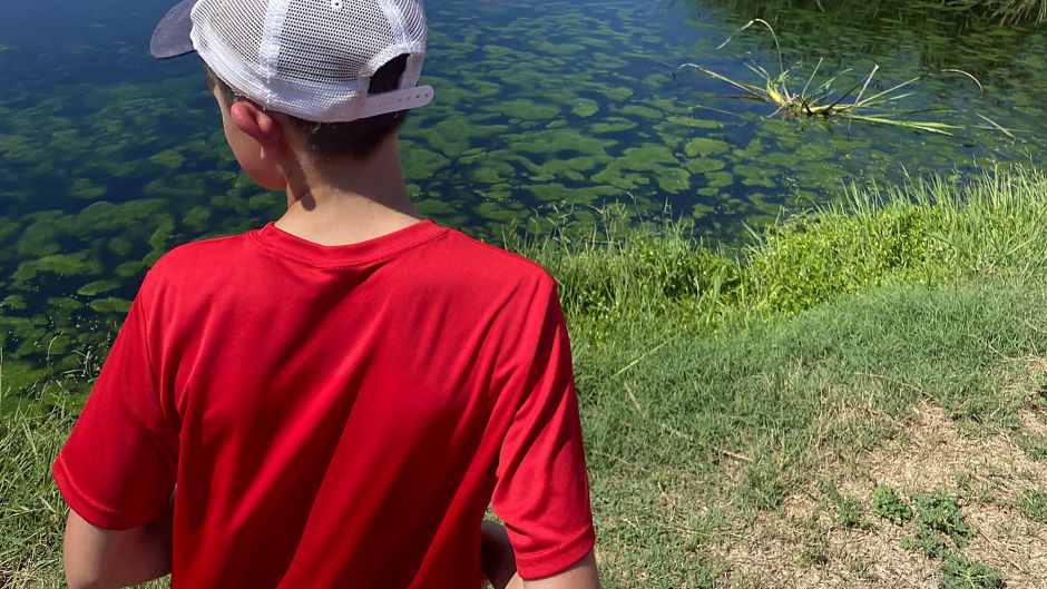 a boy in a red shirt by a body of water