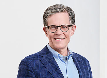 a man wearing glasses and a blue jacket