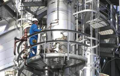 a man in a blue overalls on a large metal tower