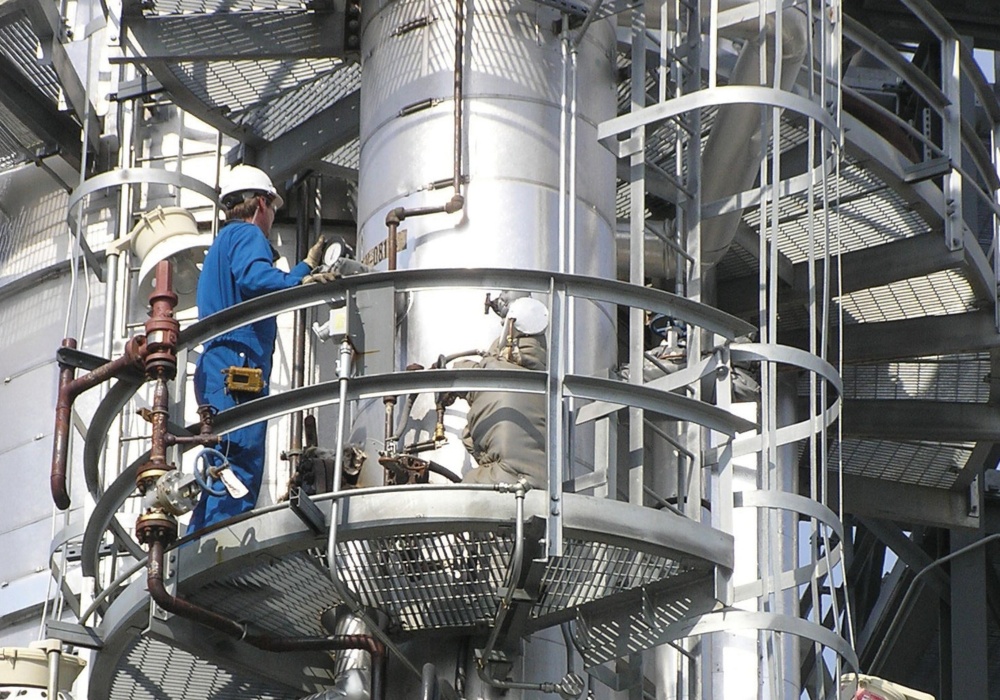 a man in a blue overalls on a large metal tower