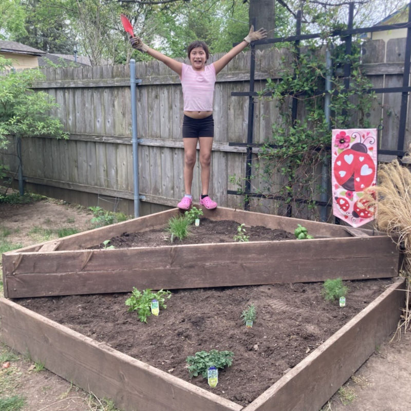 a girl standing on a raised bed of plants