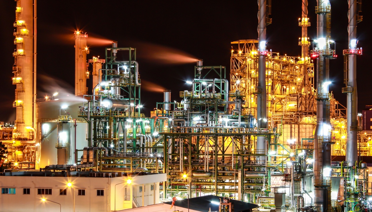 a factory at night with smoke coming out of the pipes