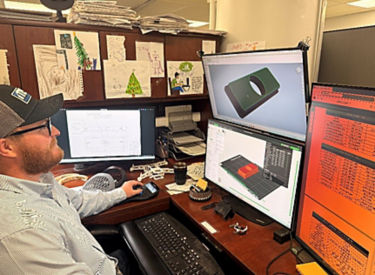 a man sitting at a desk with multiple computer screens