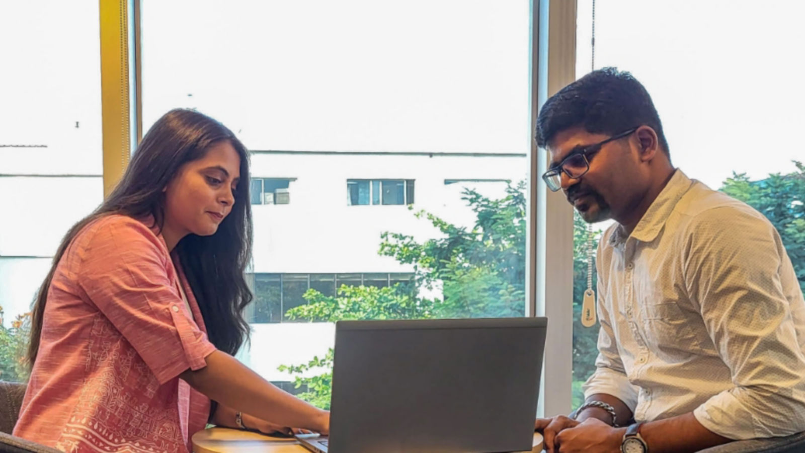 a man and woman sitting at a table looking at a laptop