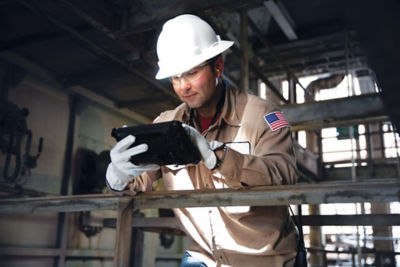 a man in a hard hat and gloves using a tablet