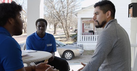 People sitting on a porch talking around a table