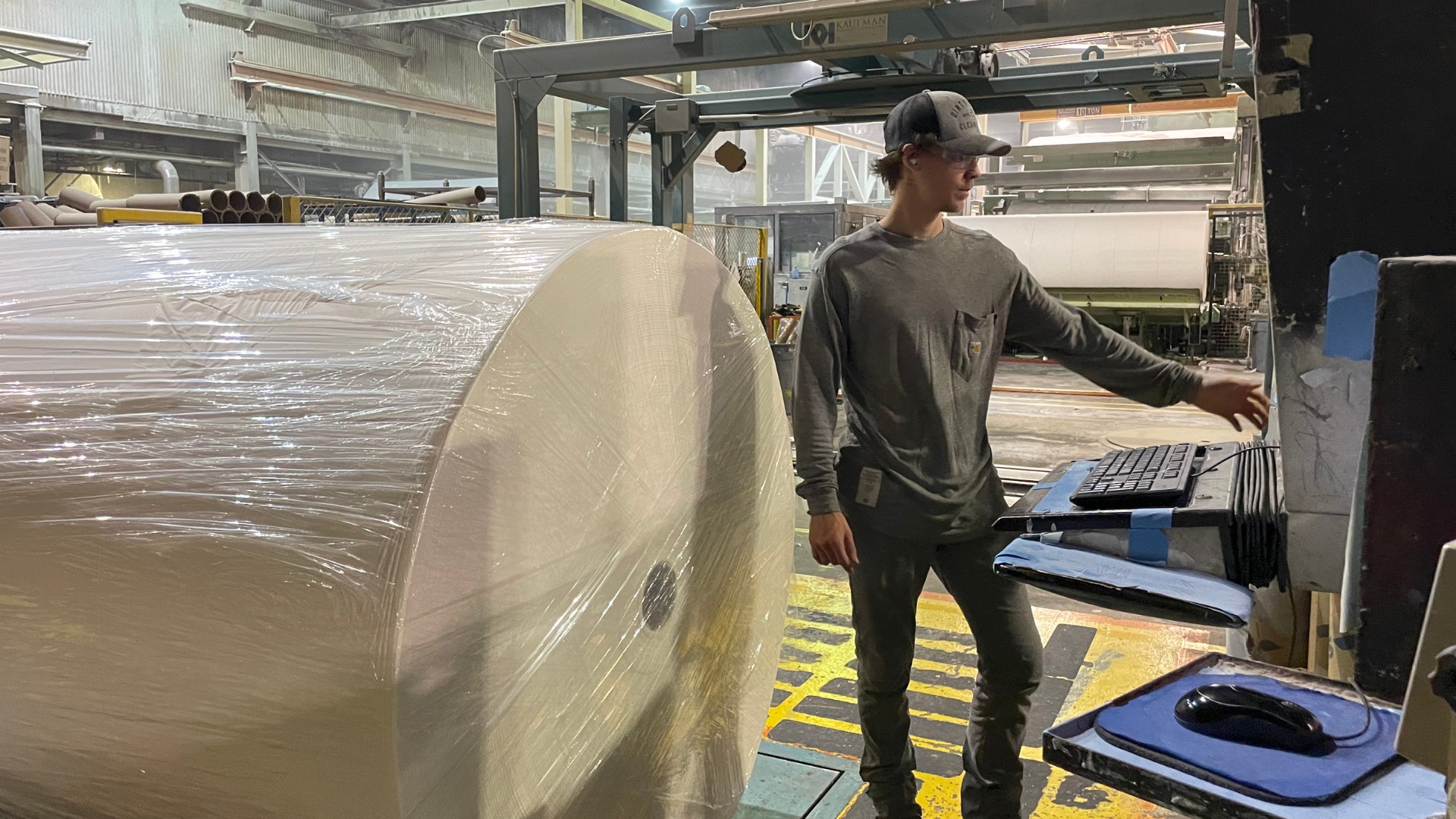 A Georgia-Pacific employee stands in front of new equipment that will make paper for Angel Soft® and strategic private label bath tissue.