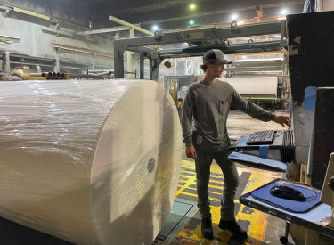 a man standing next to a large roll of paper