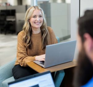 a woman sitting at a table with a laptop