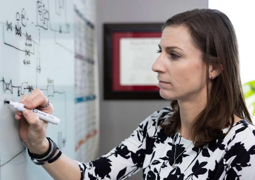 a woman writing on a whiteboard
