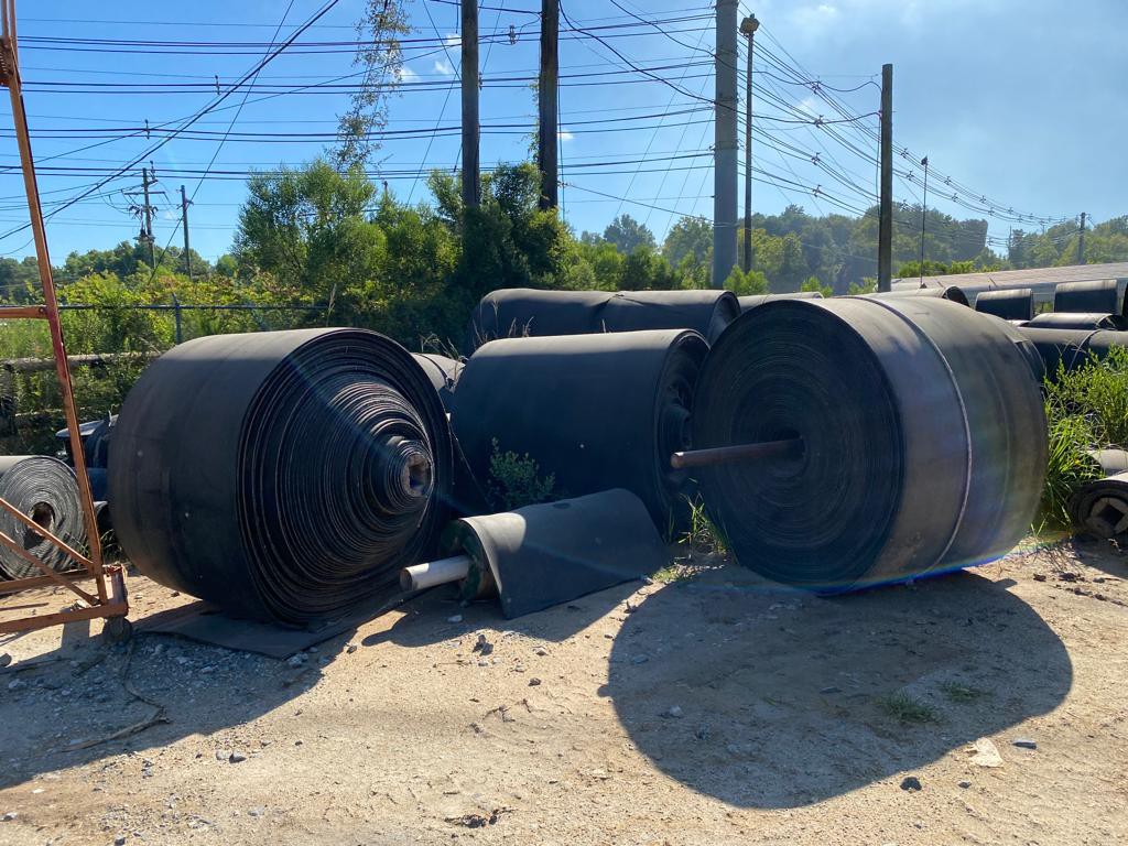 Before picture of conveyor belt rolls in Cedar Springs scrap yard before being hauled away to be recycled. 