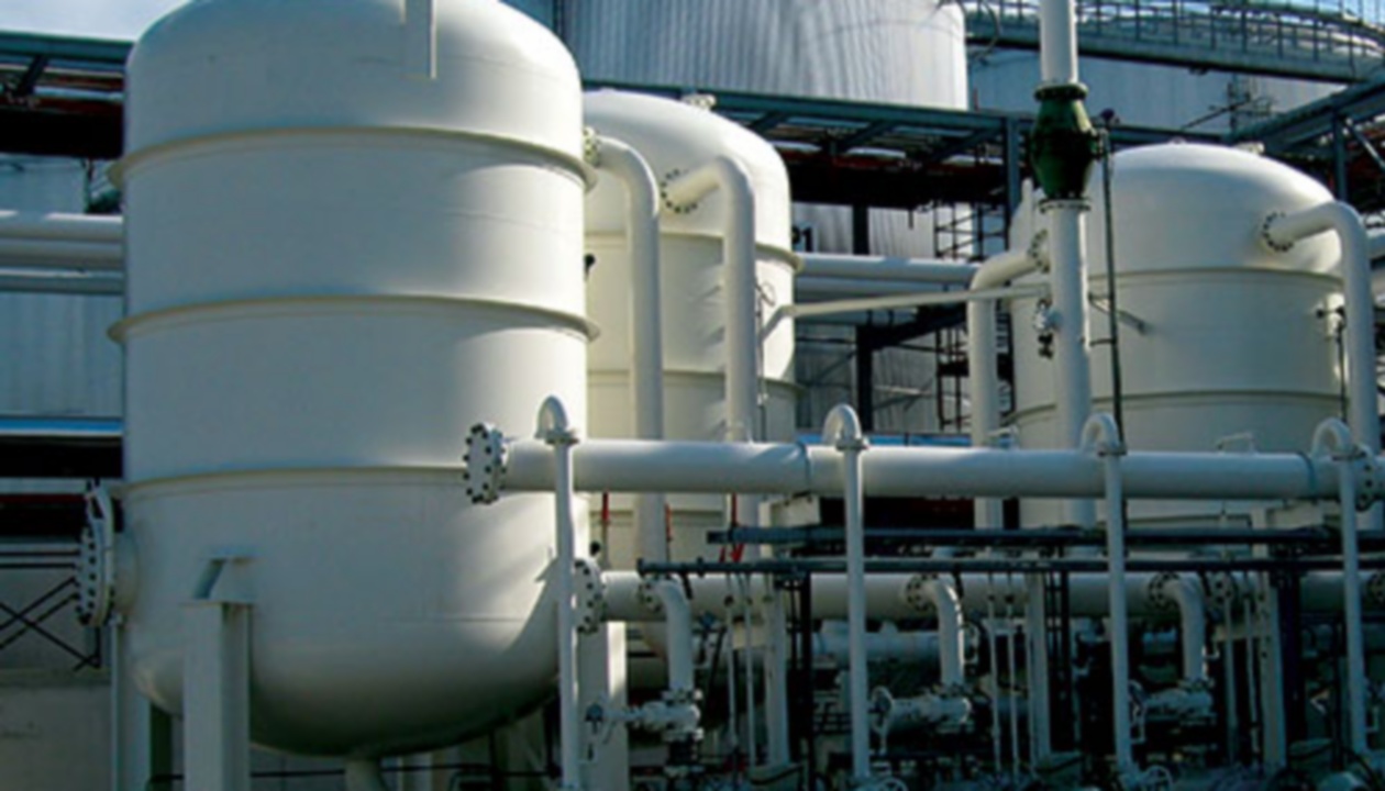 a large white tanks outside of a factory