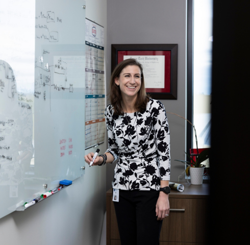 a woman standing in front of a whiteboard
