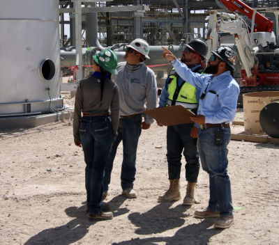 a group of people wearing hard hats and standing in front of a factory