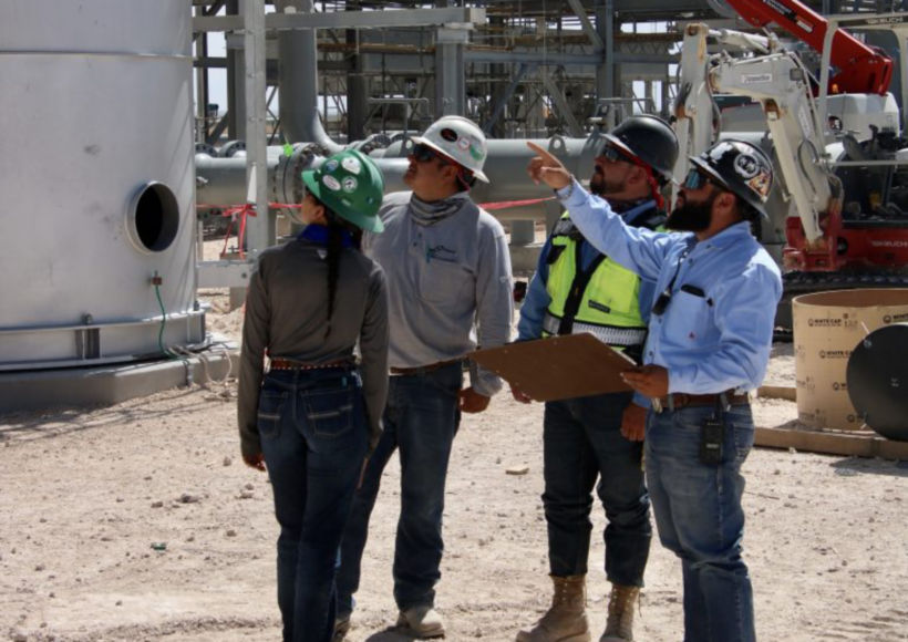 a group of people wearing hard hats and standing in front of a factory