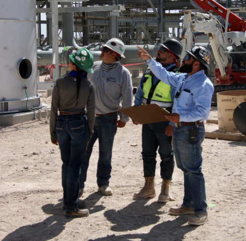 a group of people wearing hard hats and standing in front of a factory