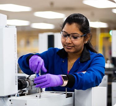 a woman wearing gloves and working on a machine